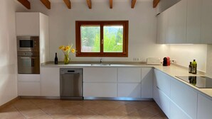 A modern kitchen with built-in appliances, a window, and a tiled floor. - Vista Verde by Balearic Villas (Pollensa)