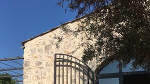 An outdoor seating area with a table set for two, a stone wall, and a metal gate.