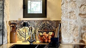 A kitchen with a stone wall, a window above the sink, and a tiled backsplash.