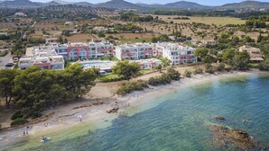 Ein Hotel an der Küste mit mehreren Gebäuden, einem Strand und klarem, blauem Wasser.