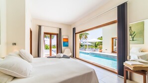 Ein Hotelzimmer mit einem großen Bett, Blick auf einen Swimmingpool und einer Tür, die nach draußen führt.