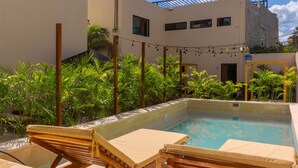 A pool area with lounge chairs, a clear pool, and a building with multiple windows and a balcony. - Mayanah Condohotel Bacalar (Bacalar)