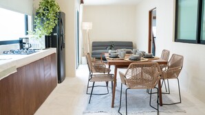 A modern kitchen with a dining area, featuring a built-in refrigerator, a coffee maker, and a dining table with wicker chairs. - Mayanah Condohotel Bacalar (Bacalar)
