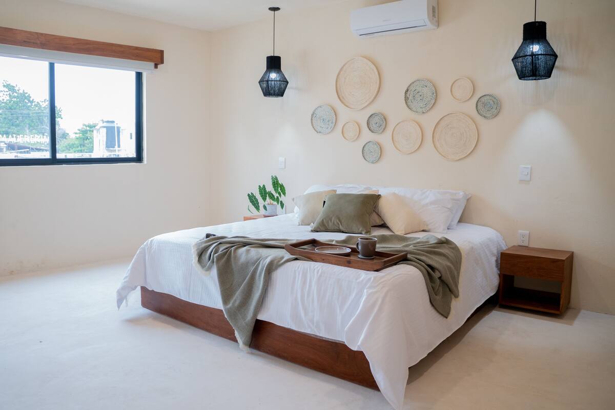 Une chambre avec un grand lit, une table de chevet, des éléments de décoration murale et une fenêtre.