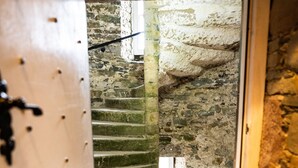 Una stretta scala con ringhiera in legno e un tappetino all'estremità inferiore.