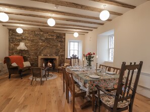 A dining room with a stone fireplace, wooden beams, and a table set for four. - Freswick Castle (Wick)
