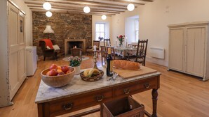Cucina spaziosa con parete in pietra, travi in legno e zona pranzo con tavolo apparecchiato per quattro.