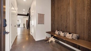 Un couloir moderne avec un mur d’accent en bois, un banc avec des coussins et un escalier en arrière-plan.