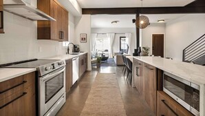 Une cuisine moderne dotée d’un îlot central, de fours encastrés et d’un coin repas avec un canapé et des chaises.