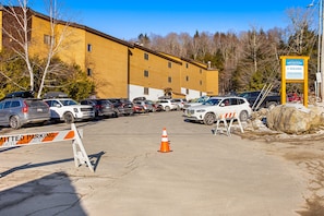 Park your car in the designated parking area adjacent to the building with multiple windows.