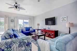 Una sala de estar con un sofá azul, un aparador rojo y un ventilador de techo.