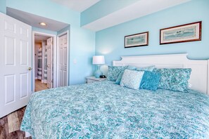 Un dormitorio con una cama, una mesita de noche, una lámpara y dos cuadros en la pared.