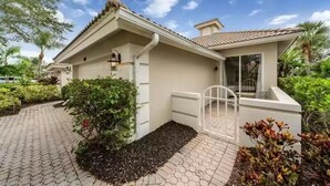 A house with a tiled roof, a front porch, and a garden area. - Beautiful Detached Home in Fiddlers Creek on the Golf Course (Naples)
