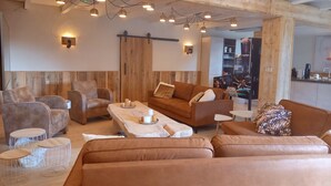 A cozy living room with a brown leather sofa, a coffee table, and a wooden accent wall. - Pura Vida Panorama : Enjoy life ! (Oud Ade)