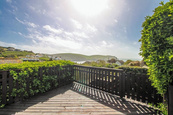A wooden bridge leading to a scenic area with hills and a clear sky.