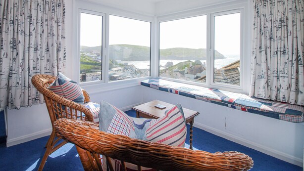 A room with a view of the sea, wicker furniture, and patterned curtains. - Eddystone (Kingsbridge)
