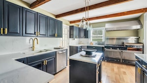 Une cuisine moderne avec des meubles de couleur sombre, un plan de travail blanc et une cuisinière en acier inoxydable.