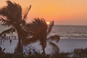 A beach scene with palm trees, a sunset, and people walking. - 1209 SE 32nd Ter (Cape Coral)