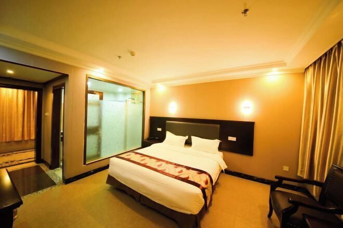 A hotel room with a bed, a desk, a chair, a large mirror, and a sliding door.