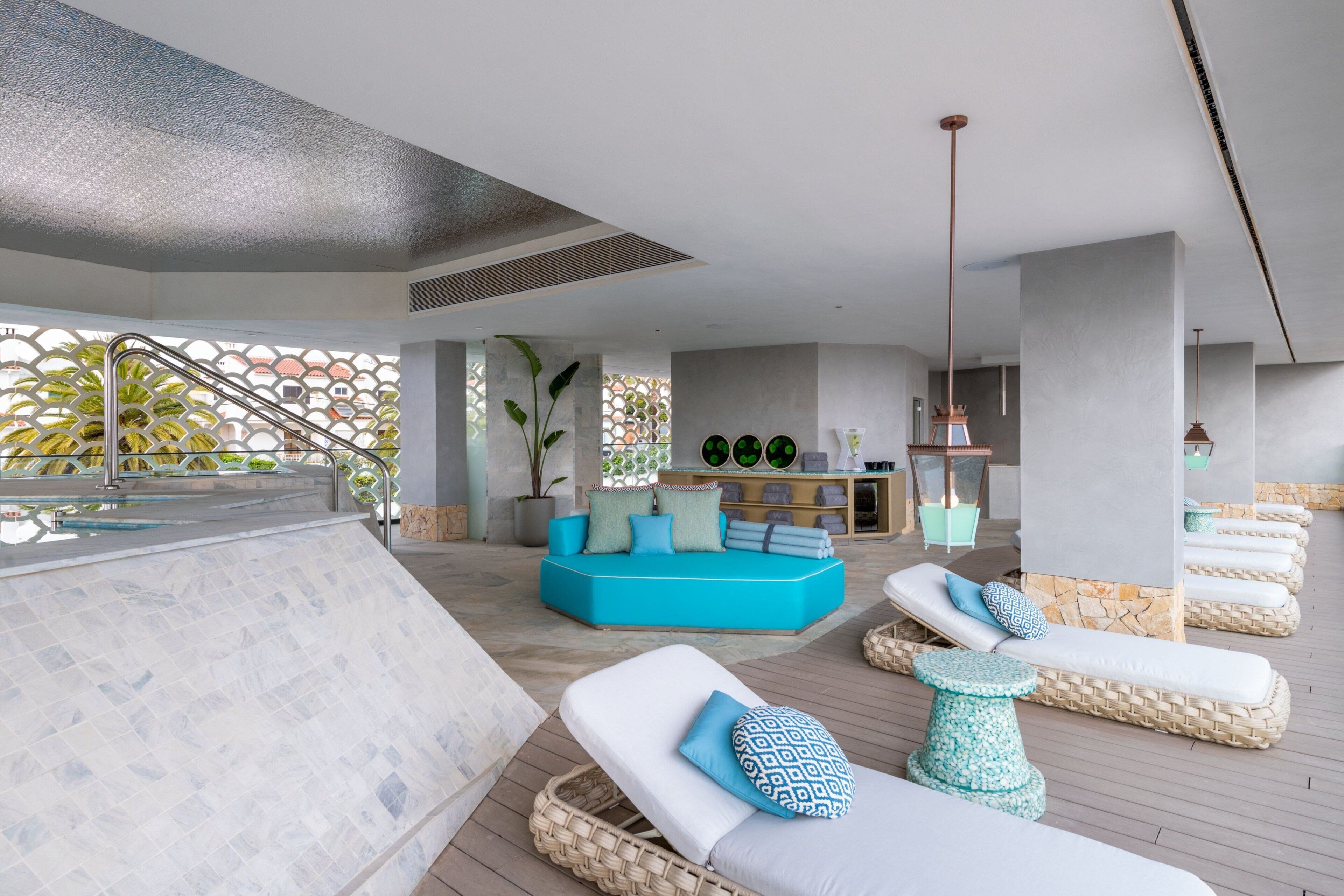 Un área interior de piscina moderna con sillones reclinables, una zona de estar y una escalera.