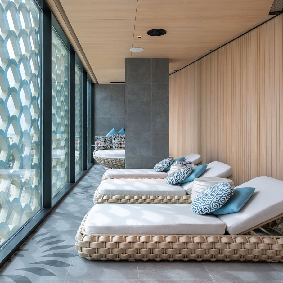 Un área de spa con tres sillones reclinables, una ventana con diseño y suelo de baldosas.