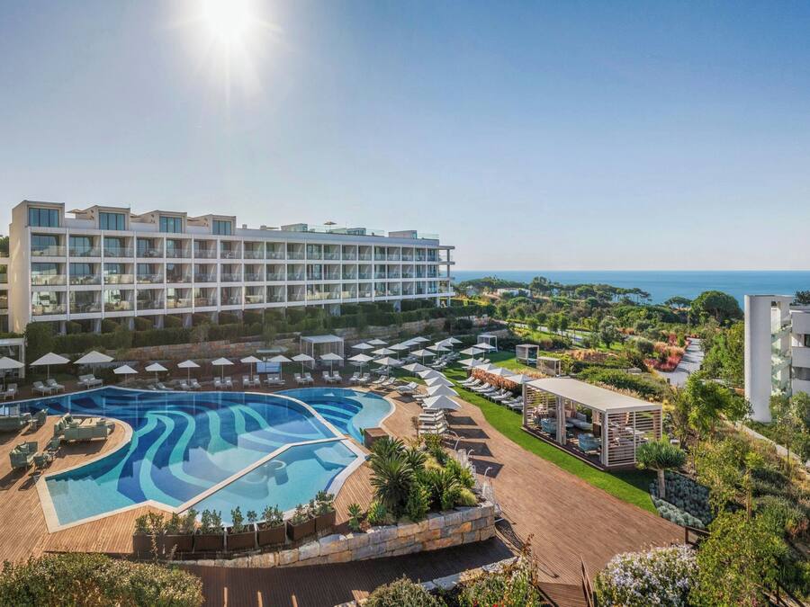 Et resort med en stor swimmingpool, flere opholdsområder og havudsigt.