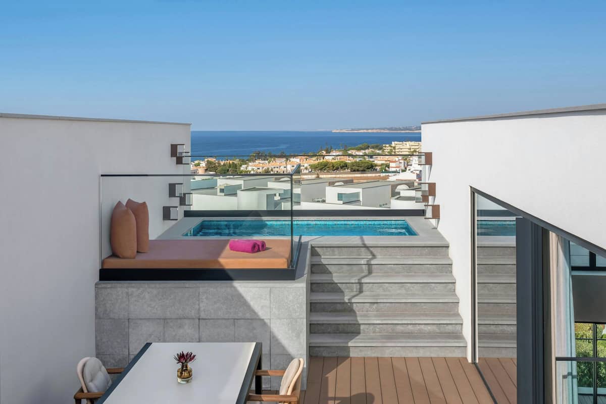 A modern rooftop terrace with a pool, seating area, and a table.