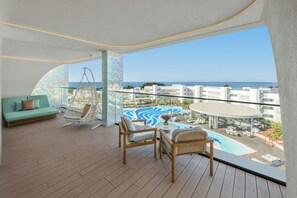 Un balcone con vista sul mare, una piscina e una zona relax con posti a sedere.