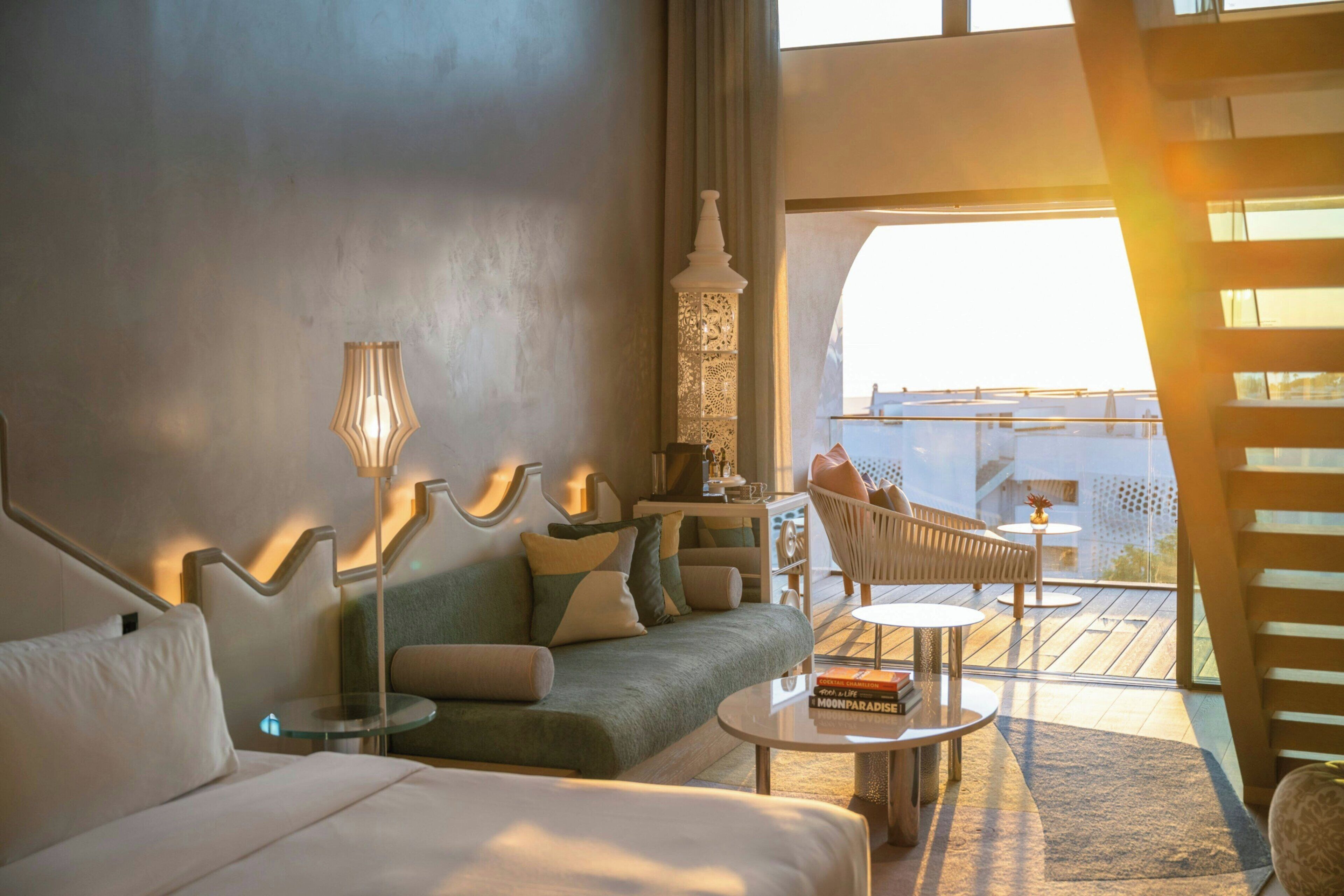 Una habitación de hotel moderna con sofá, una mesita y un balcón con vistas.