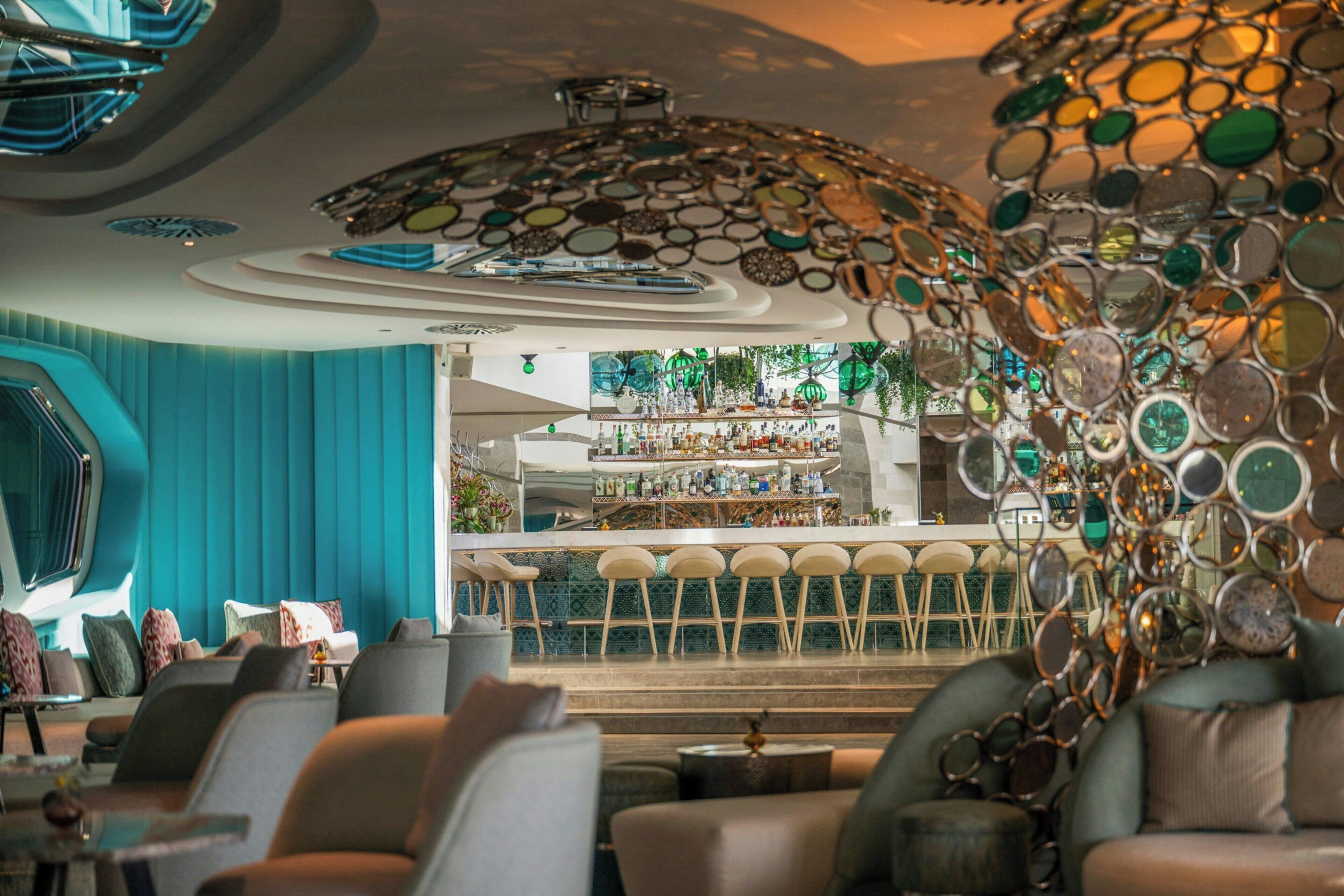 A modern bar area with a bar counter, seating, and a decorative ceiling.