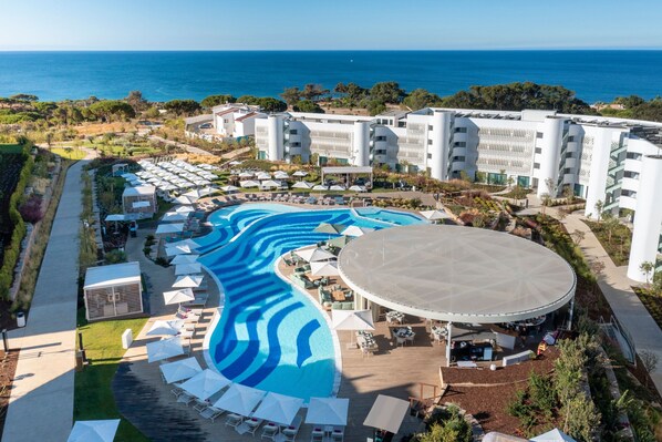 Relax by the resort's large pool surrounded by lounge chairs and umbrellas, with a view of the ocean.