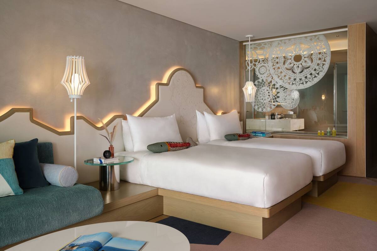 A hotel room with a large bed, a sofa, a small table, and a decorative wall piece.