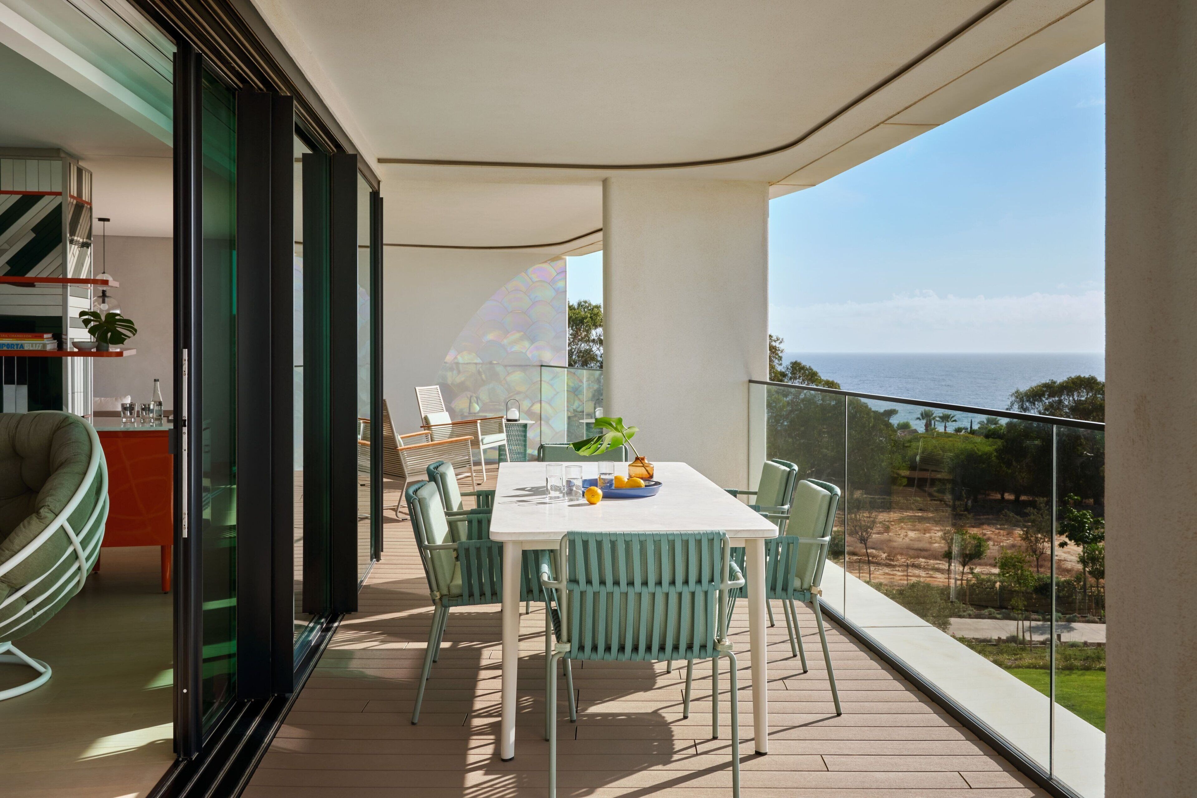 Un balcon avec une table et des chaises pour prendre les repas, un canapé et une vue sur la mer.