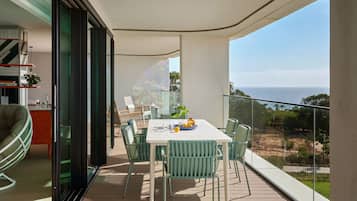 Un balcon avec une table et des chaises pour prendre les repas, un canapé et une vue sur la mer.