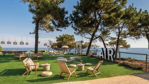 Un área de estar al aire libre con sillas y mesas, un letrero que dice “AIR” y vista al mar.