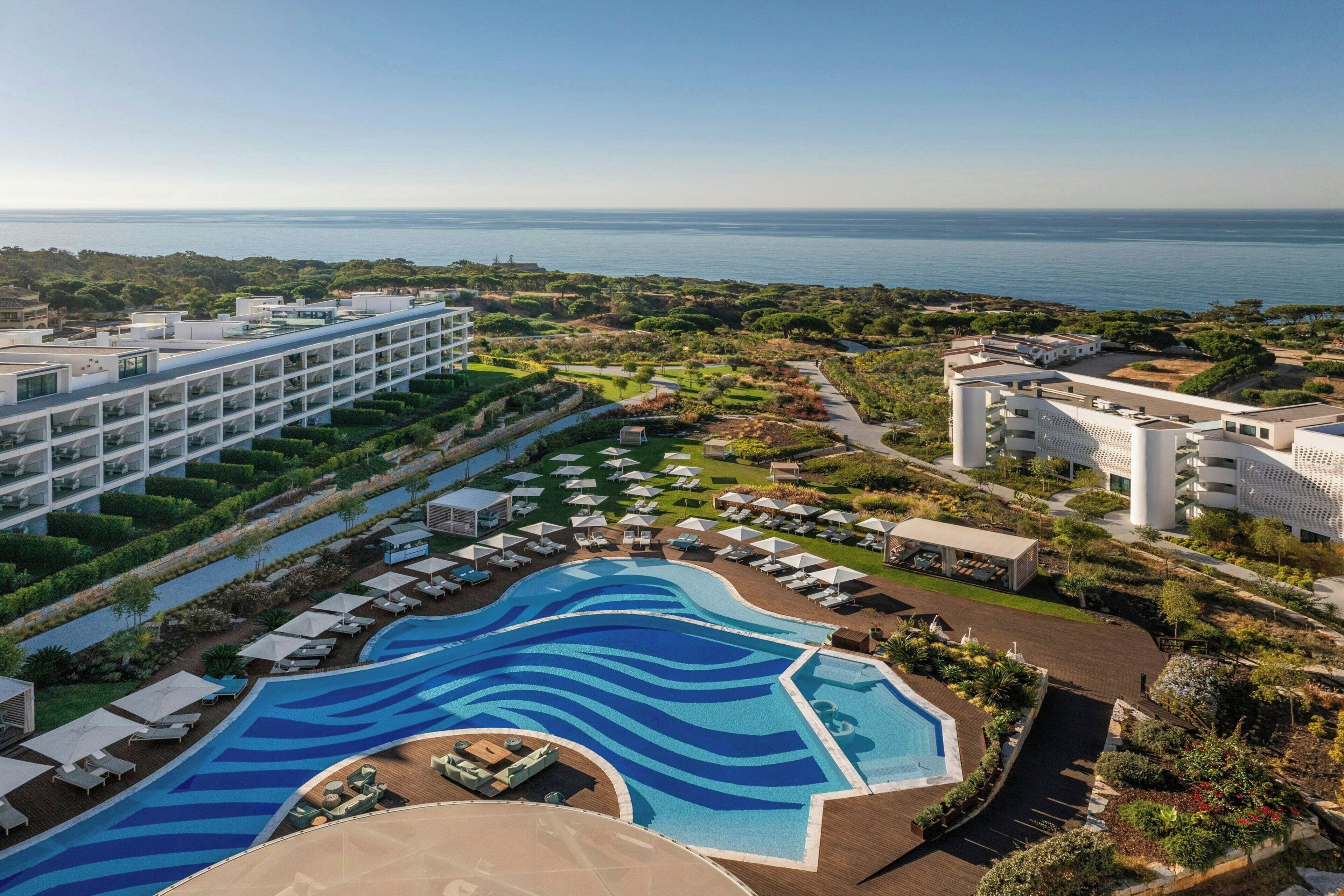 Un resort con una grande piscina, diversi edifici e vista sul mare.