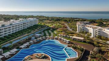 Ein Resort mit großem Pool, mehreren Gebäuden und Blick auf das Meer.