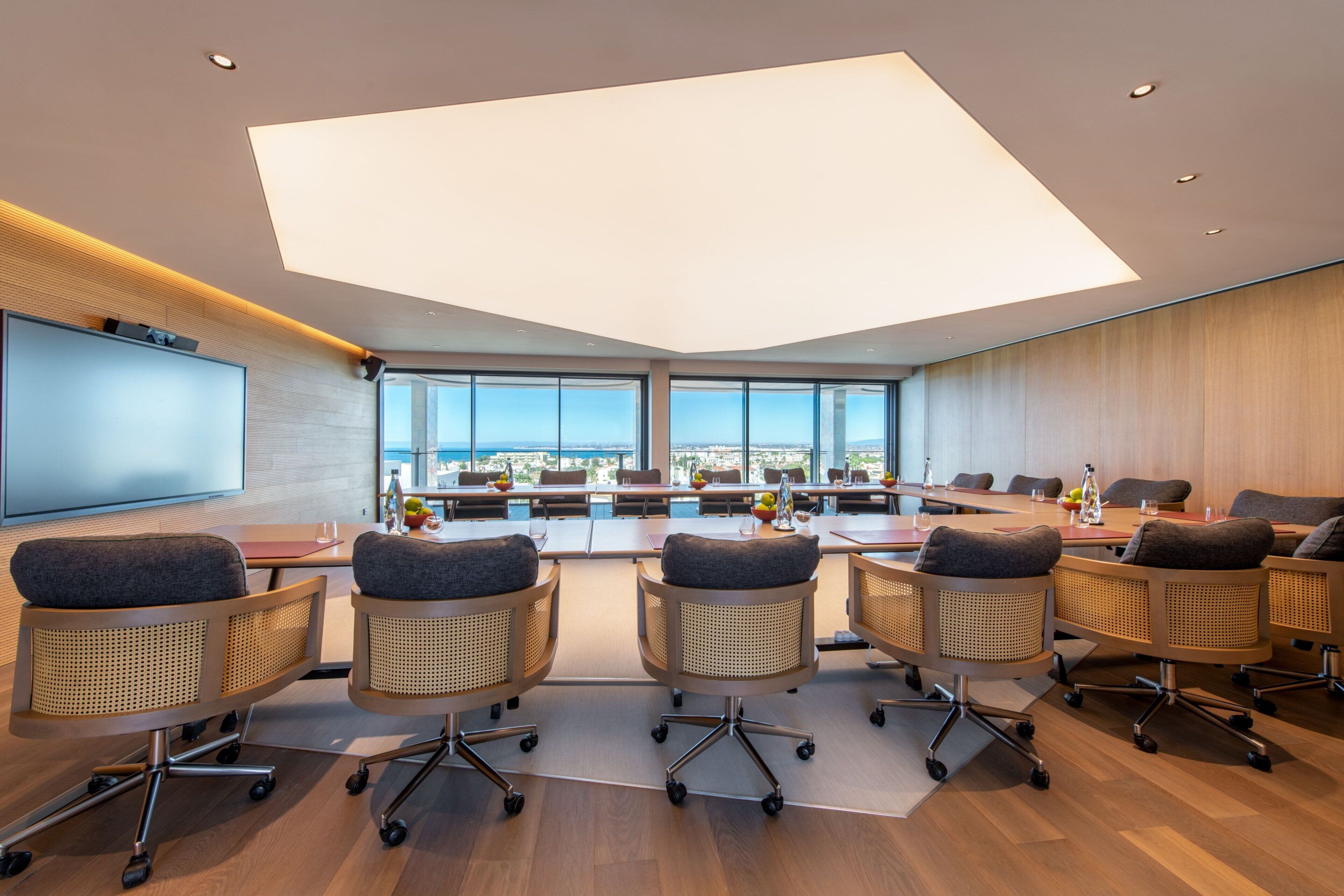 A modern conference room with a large table, comfortable chairs, and a city view through large windows.
