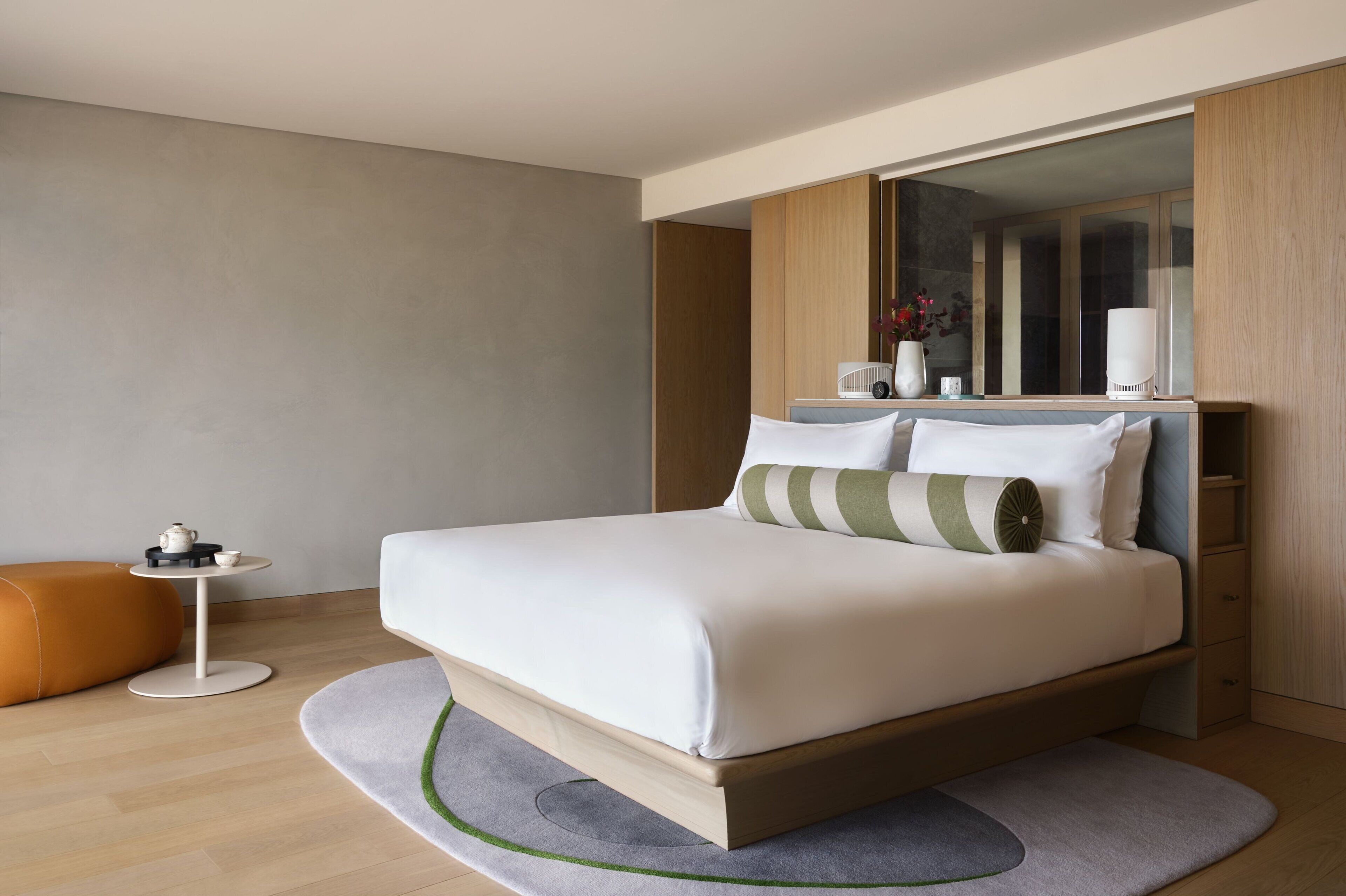 Un dormitorio moderno con una cama grande, una mesita redonda pequeña y un sofá.