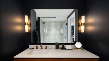 A modern bathroom with a large mirror, two wall-mounted lights, a white sink, and a wooden vanity.