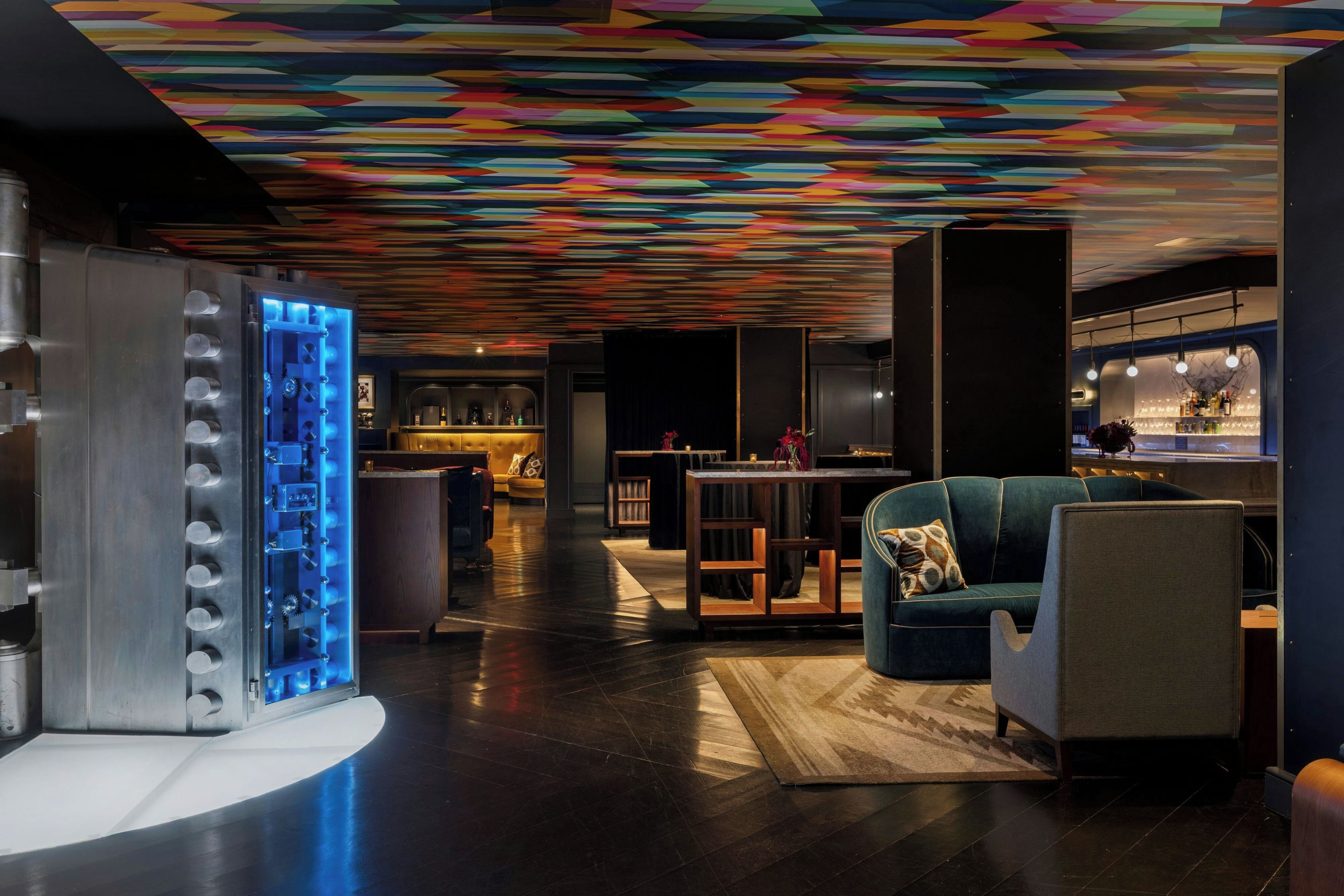 Un interior moderno con techo de diseño geométrico, una zona de bar y diferentes disposiciones de asientos.