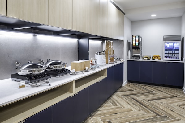 Een moderne keuken met roestvrijstalen apparatuur, een koffieapparaat en een automaat.