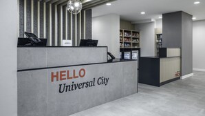 A reception desk with a 'HELLO Universal City' sign, a counter with a computer, and a storage area with shelves. - TownePlace Suites by Marriott San Antonio Universal City/Live Oak (Selma)