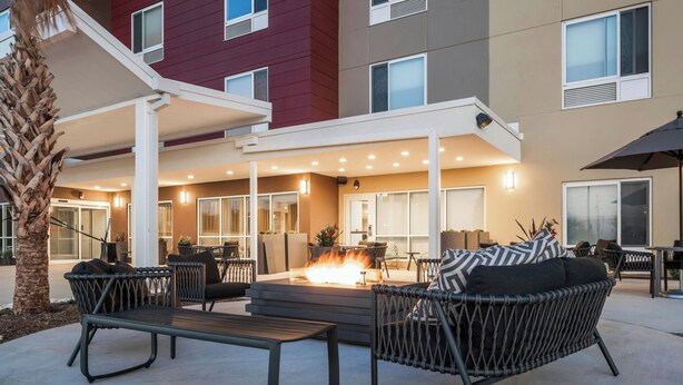 An outdoor seating area with wicker furniture, a fire pit, and a covered walkway. - TownePlace Suites by Marriott San Antonio Universal City/Live Oak (Selma)