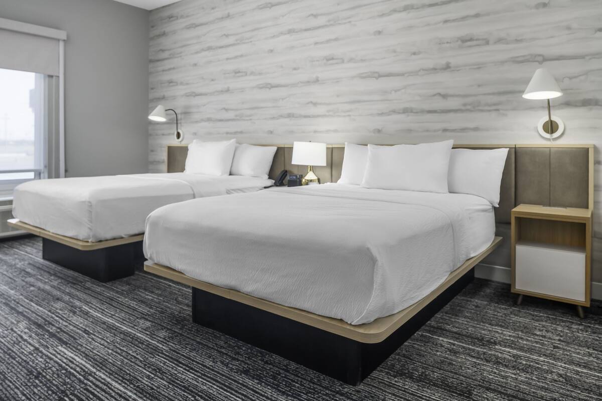Une chambre d’hôtel avec deux lits, un mur décoré d’un motif imitant le marbre et un design moderne.