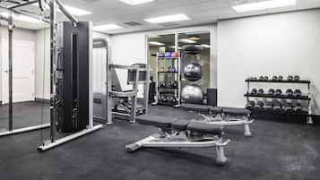 A gym with various exercise equipment, including a bench press, dumbbells, and a weight stack.