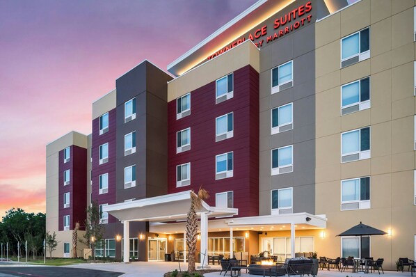 A multi-story hotel with a modern facade, a covered outdoor seating area, and a sign indicating it is a Marriott property.