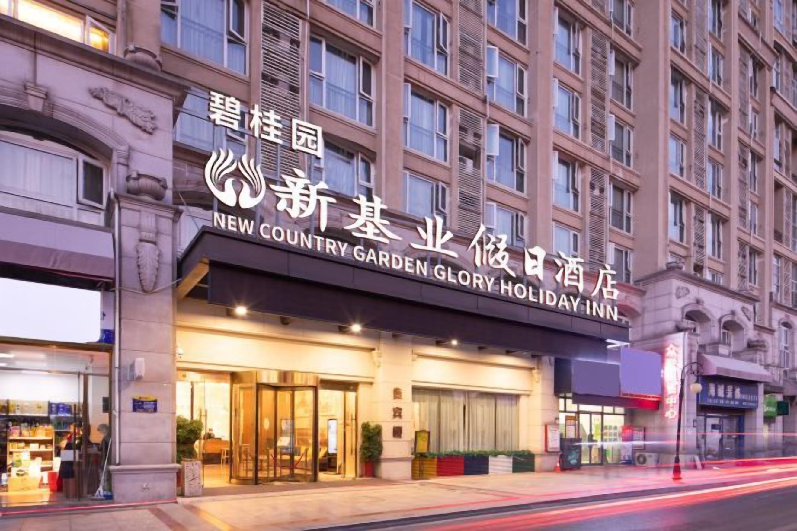 Un hotel con un letrero grande en idioma extranjero, varios pisos y una entrada bien iluminada.