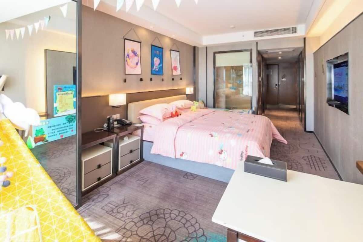 Ein modernes Hotelzimmer mit einem großen Bett, Nachttischen, einem Schreibtisch und einem Spiegel.