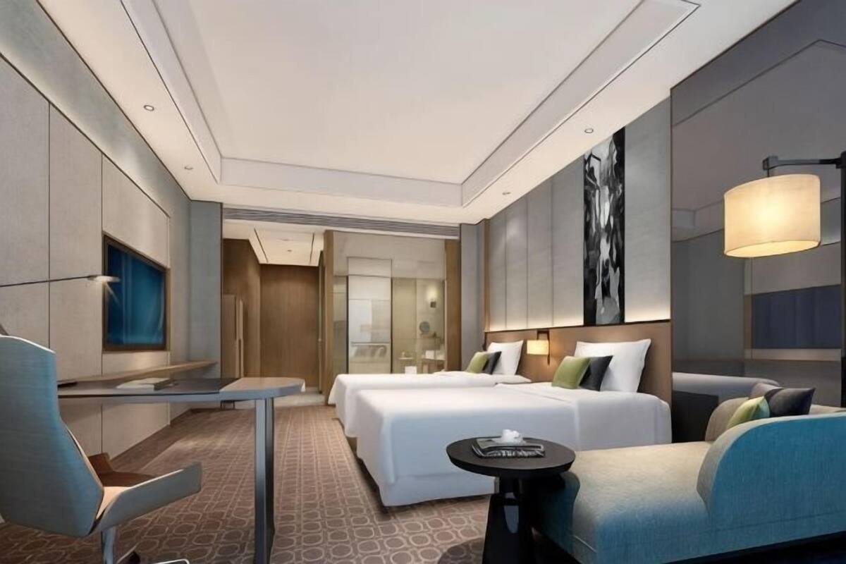Ein modernes Hotelzimmer mit Bett, Schreibtisch, Sessel, Sofa und einem kleinen Tisch.